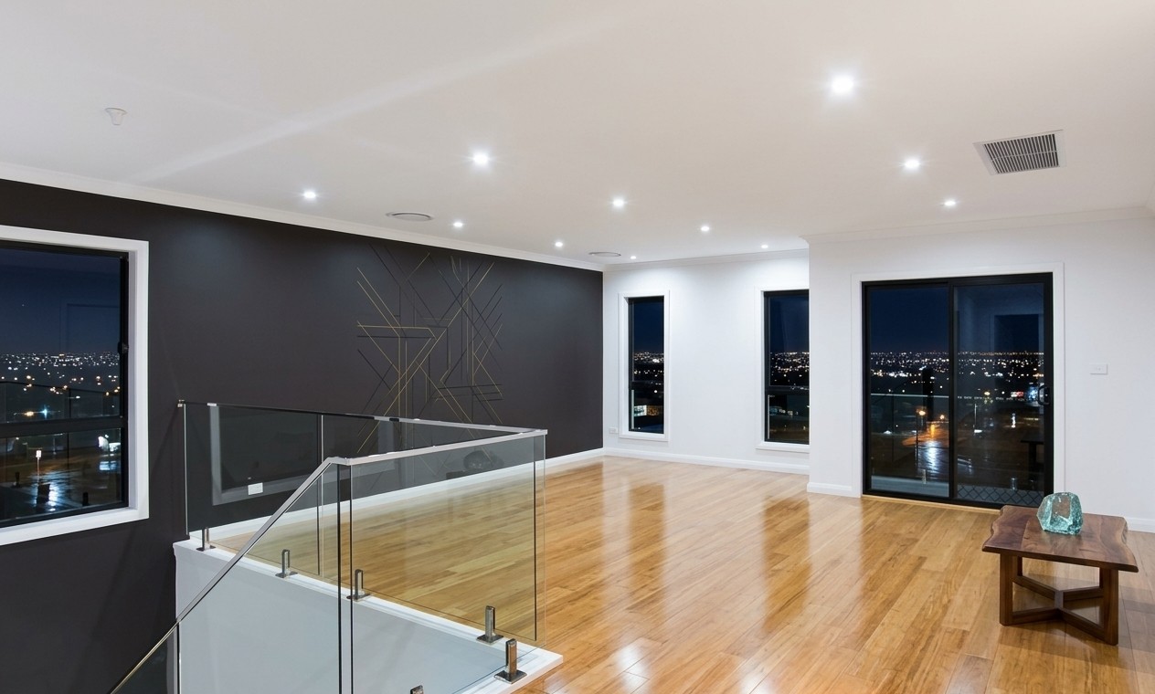 An upstairs living area with a glass balustrade in an Elegant Homes NSW build